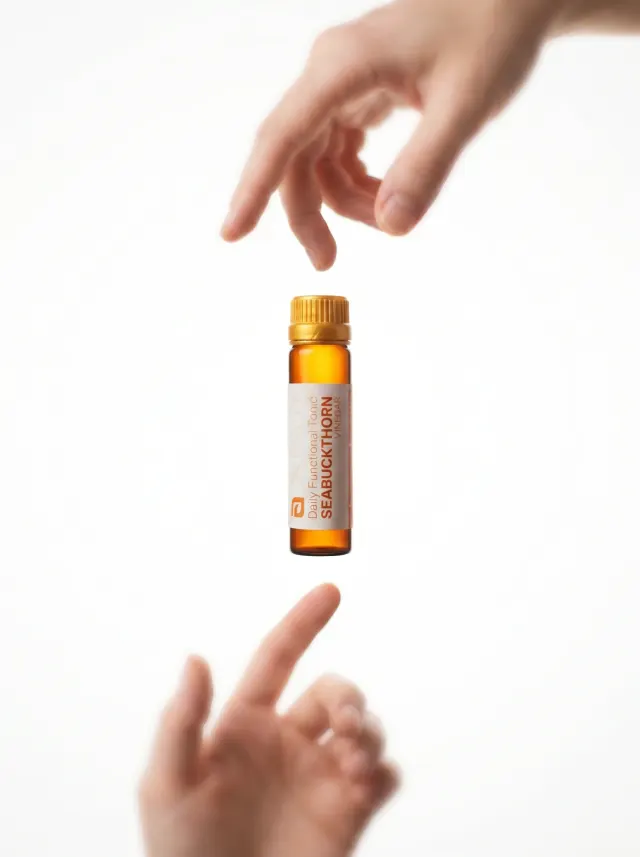 A vial of Sea Buckthorn Vinegar passed between two hands